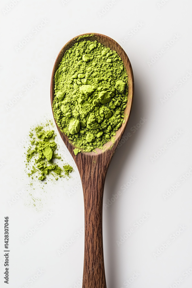 Wooden spoon with green dried matcha powder close up detail on white background.