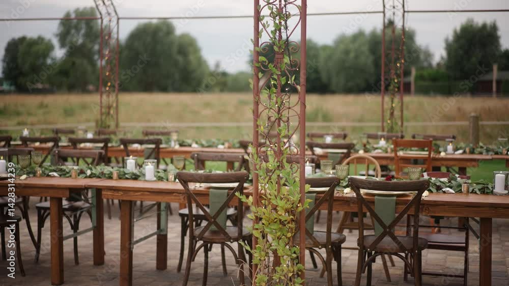 Outdoor dining setup with rustic tables and greenery at a countryside location before a gathering