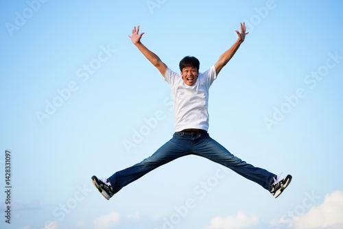 Obraz na płótnie Carefree young man is jumping with raised arms and legs spread w salonie