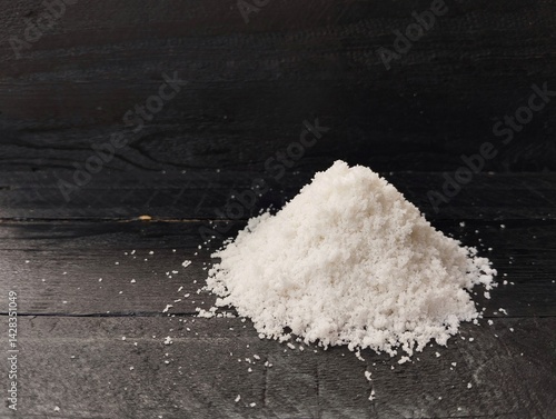 Pile of salt with black wooden table background. Food ingredient, Copy space 