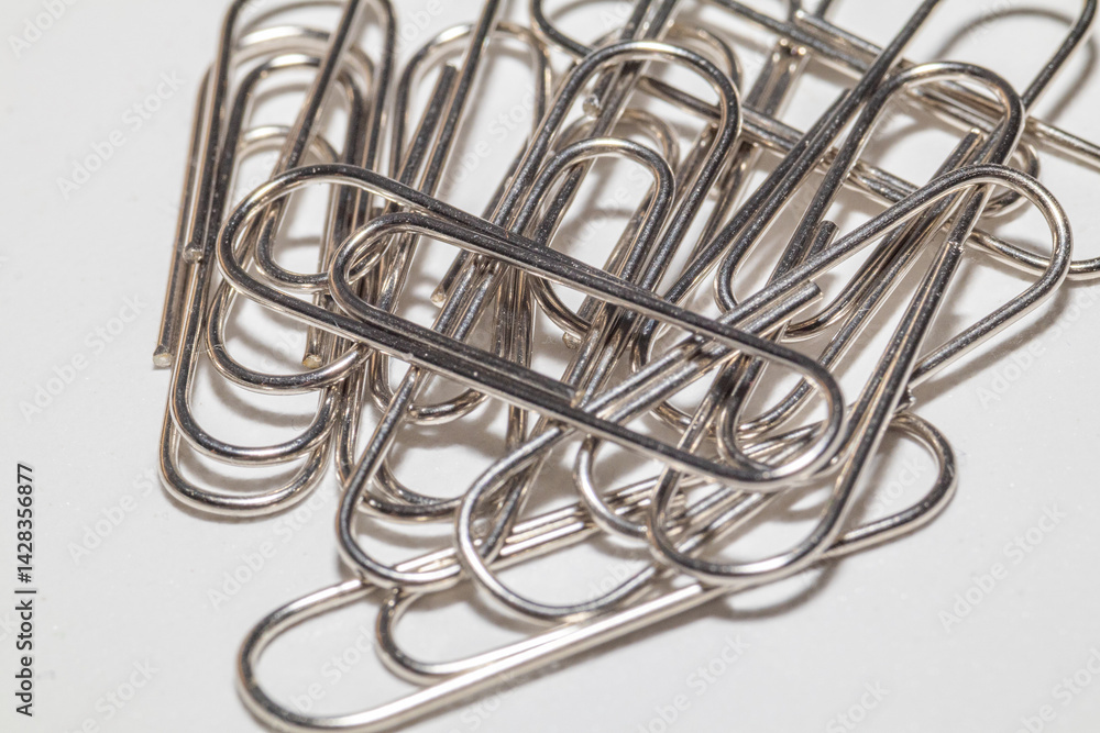 A pile of shiny silver paper clips on a white background. A pile of shiny silver paper clips on a white background.