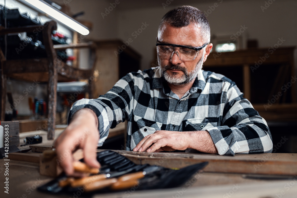Carpenter sitting in his workshop restoring old piece of furniture with carving tool. Carpenter sitting in his workshop restoring old piece of furniture with carving tool.