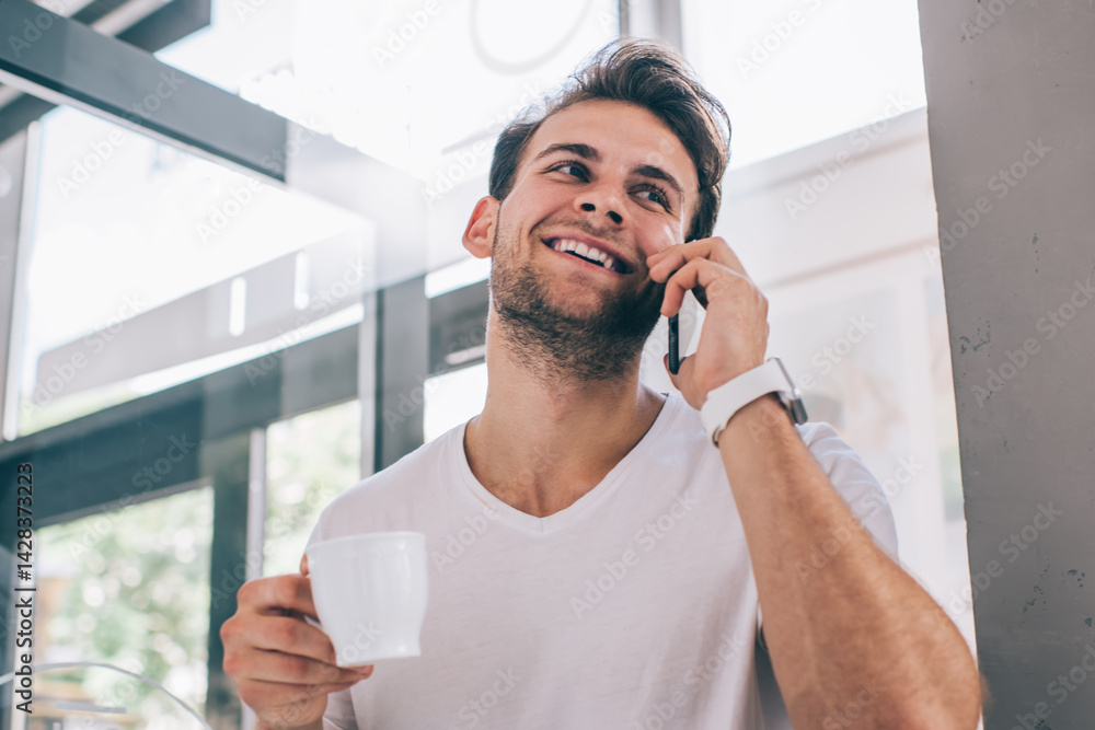 Satisfied young male speaking on mobile phone in cafe
