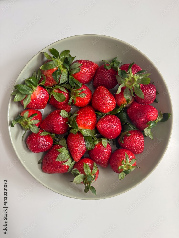 Delicious fresh red strawberries in a bowl on a white background top view