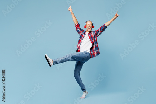 Wallpaper Mural Full body side view young middle eastern man he wear red shirt casual clothes listen to music in headphones raise up hands isolated on plain pastel light blue cyan background studio Lifestyle concept Torontodigital.ca