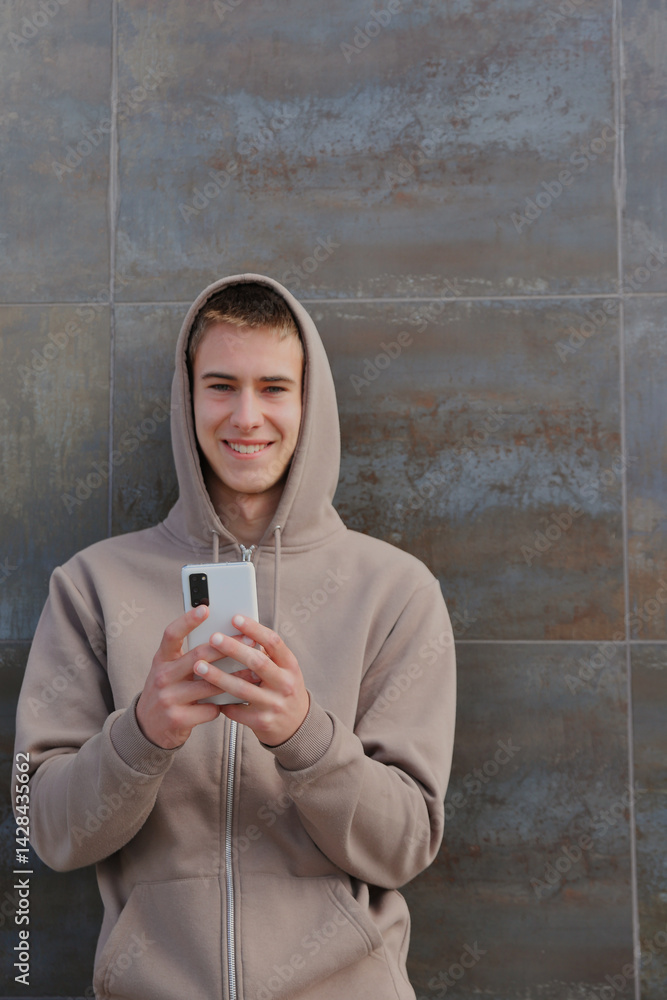 Fototapeta premium Teenager boy with smartphone, casual teen with device, young guy on black wall background