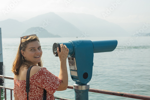 Obraz na płótnie Young 30s woman looking through a coin operated binoculars. Como Lake, Italy. w salonie