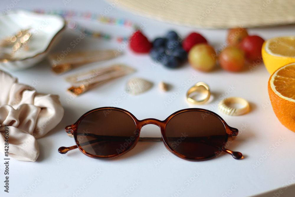 Straw hat, sunglasses, seasonal fruit, seashells and colorful accessories on white backgrounds. Cute summer essentials. Selective focus.