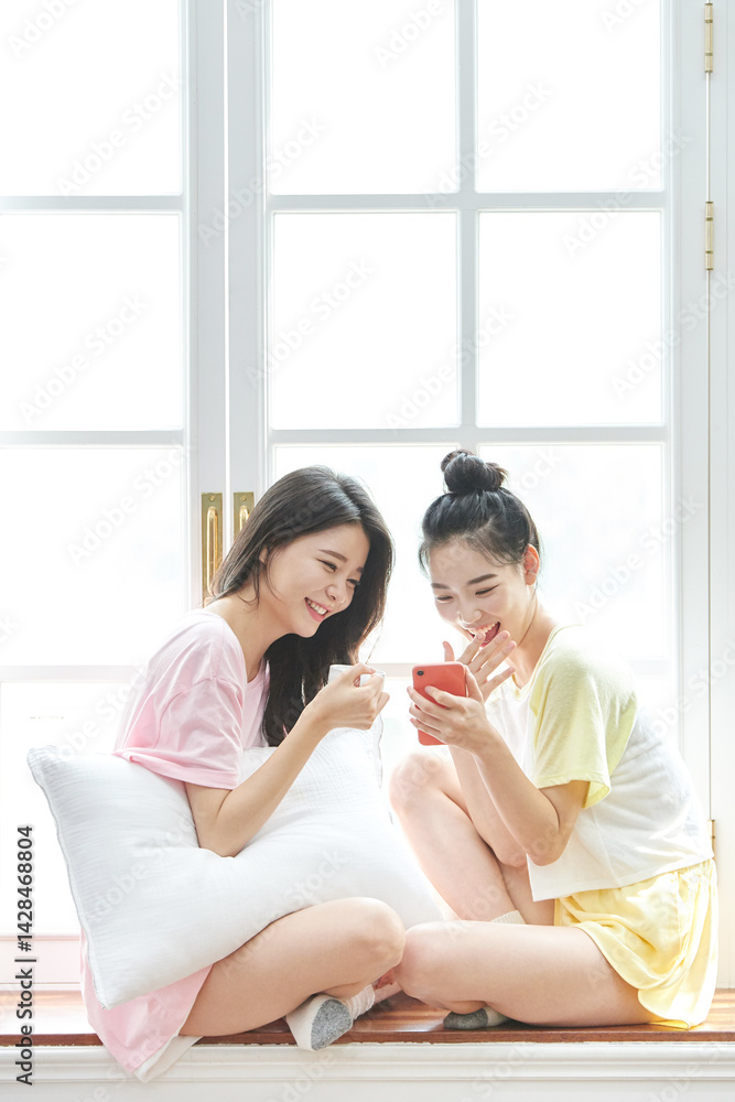 Young Women Relaxing by Window with Coffee Young Women Relaxing by Window with Coffee
