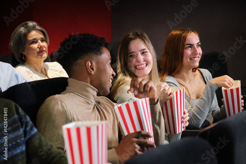 Obraz na płótnie Group of young people watching a movie at the cinema, eating popcorn and having fun w salonie