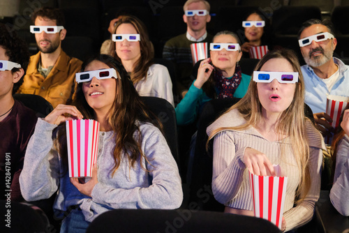 Spectators enjoying a 3d movie and eating popcorn in a movie theater