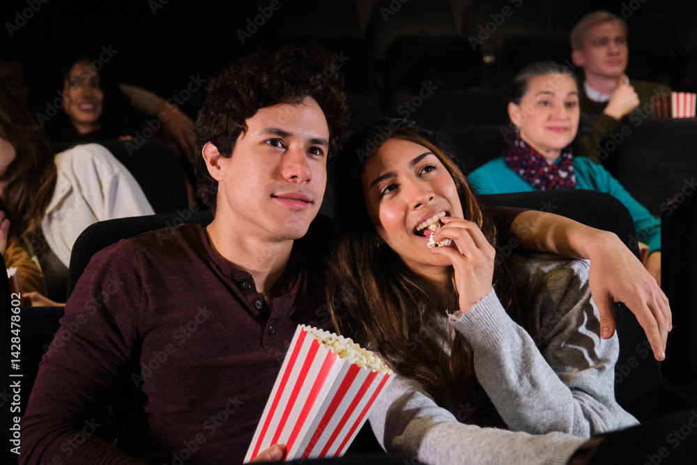 Happy latin couple enjoying film and eating popcorn in movie theater