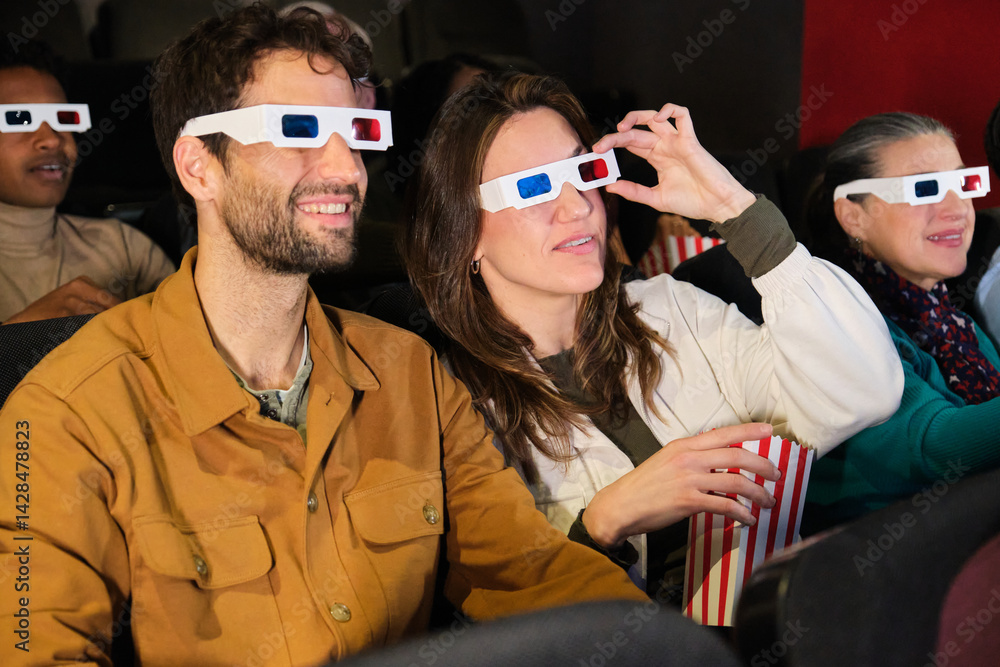 Group of friends watching a 3d film at the movie theater and eating popcorn