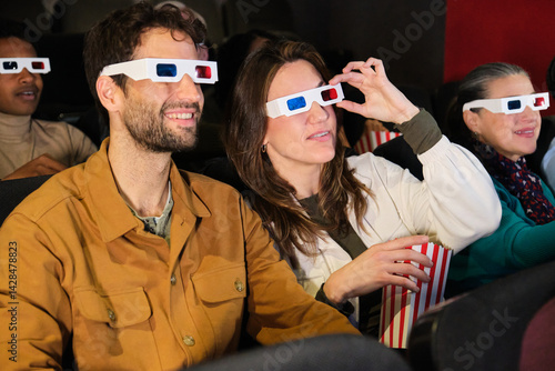 Obraz na płótnie Group of friends watching a 3d film at the movie theater and eating popcorn w salonie