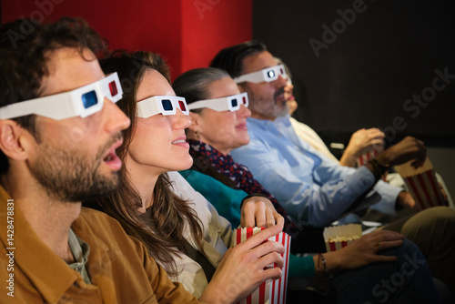 Obraz na płótnie Group of friends wearing 3d glasses watching a movie at the cinema and eating popcorn w salonie