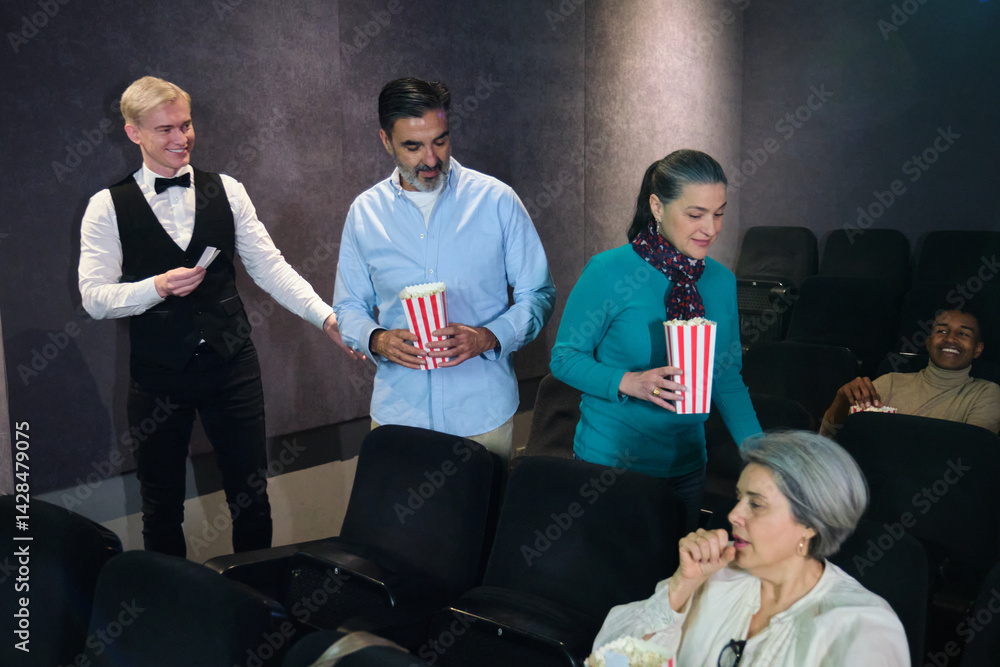 People entering movie theater showing tickets to usher and holding popcorn buckets