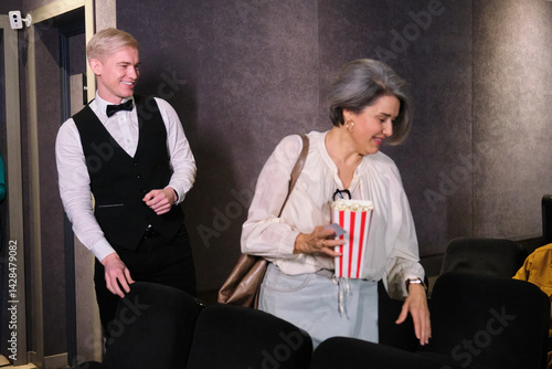 Obraz na płótnie Usher helping a woman with popcorn finding her seat in a movie theater w salonie