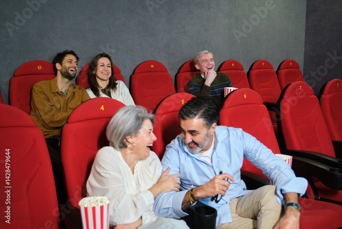 People enjoying a funny movie together at the cinema, eating popcorn and having fun