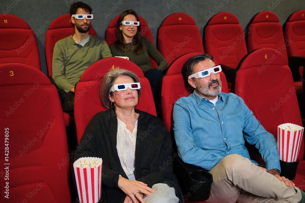People wearing 3d glasses enjoying film at movie theater, eating popcorn