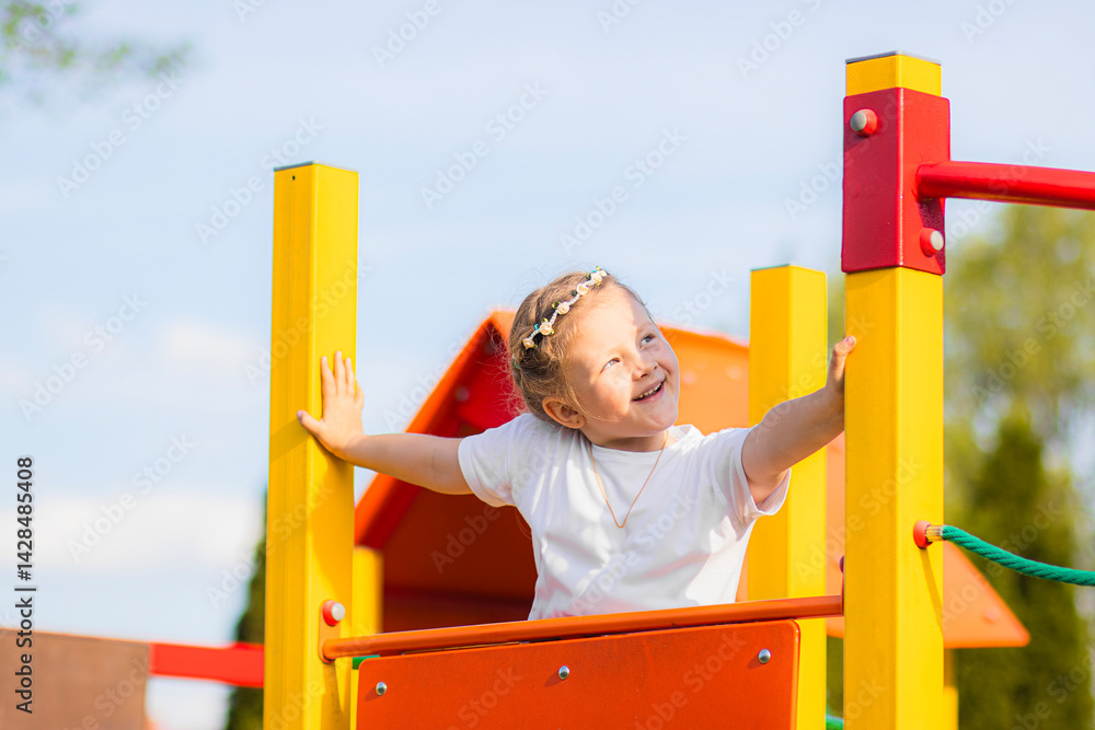 Happy blonde girl in a white T-shirt with a floral headband smiling joyfully on a vibrant, colorful playground. The background is full of playful red, yellow, green, and blue elements.