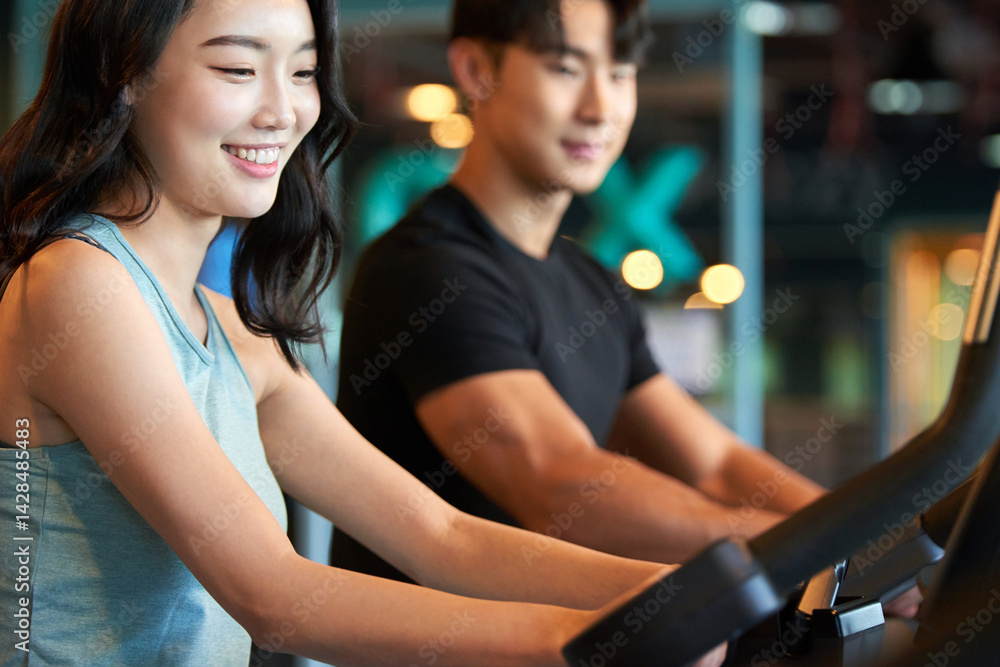 Young Asian Man and Woman Exercising Together at Gym Young Asian Man and Woman Exercising Together at Gym