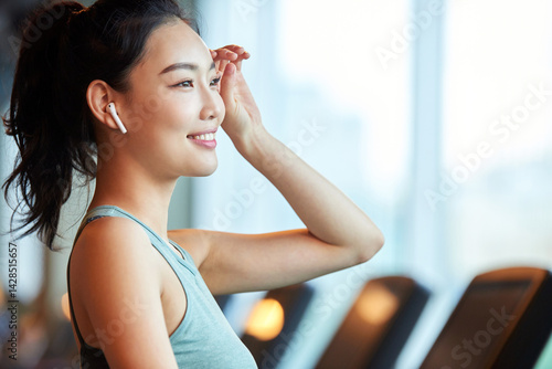 Asian Woman Smiling with Earbuds at Gym Free Download Asian Woman Smiling with Earbuds at Gym - GFXLoad