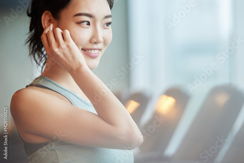 Asian Woman Smiling with Earbuds at Gym Free Download Asian Woman Smiling with Earbuds at Gym - GFXLoad