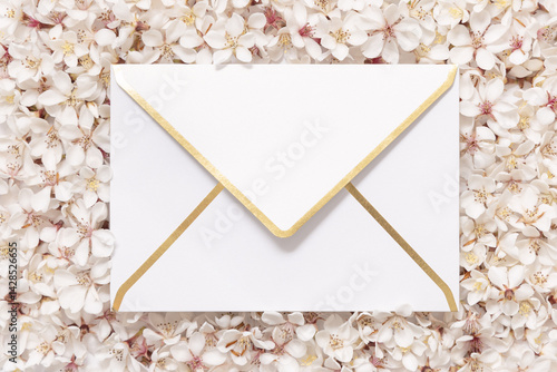 Obraz na płótnie Blank golden edge envelope over white cherry flowers top view, spring wedding mockup w salonie