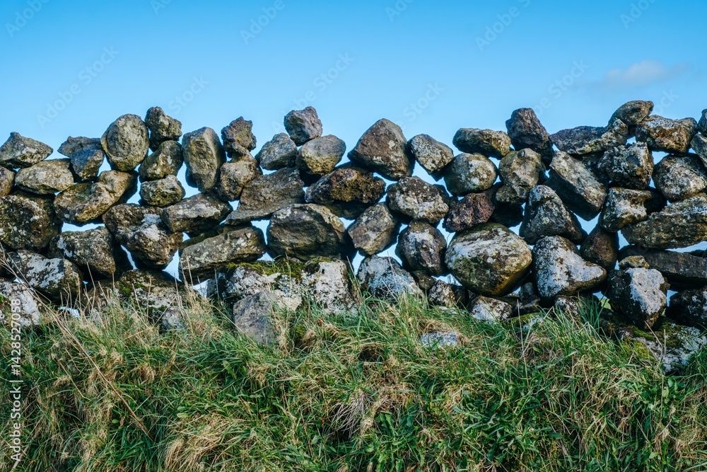 Traditional Volcanic Stone Wall Boundary Against Clear Blue Sky, Rural Agricultural Architecture. Centuries-Old Basalt Rock Fence Dividing Pastures and Fields in Terceira Island, Azores Archipelago