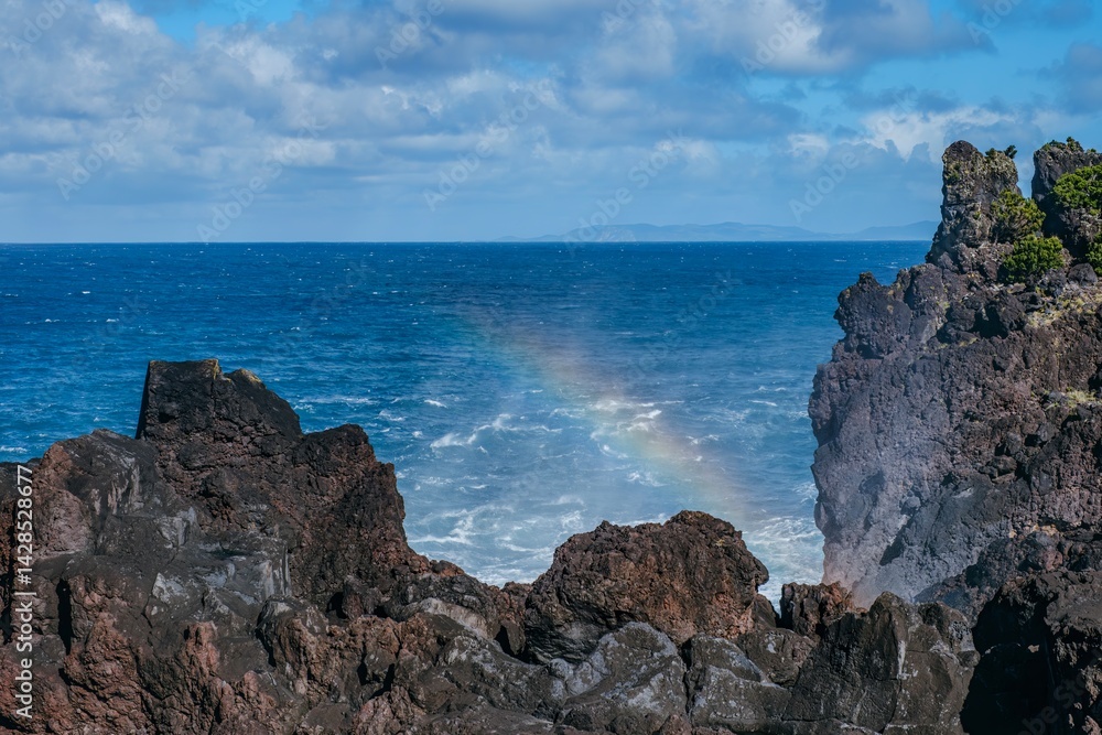 Volcanic Coastline with Rainbow Over the Atlantic Ocean. Natural Lava Rocks and Sea Spray, with a delicate rainbow forming, Sao Jorge Island, Azores, ideal for travel and nature stock content