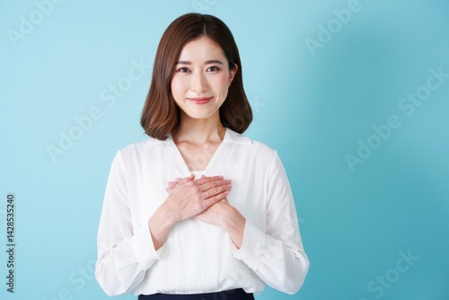 Obraz na płótnie Grateful woman holding hands on chest smiling on blue background looking at camera w salonie