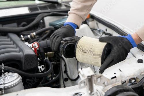 Tableau sur toile Mechanic changes the air filter in a car's engine compartment, ensuring optimal performance and cleanliness of the vehicle's air intake system