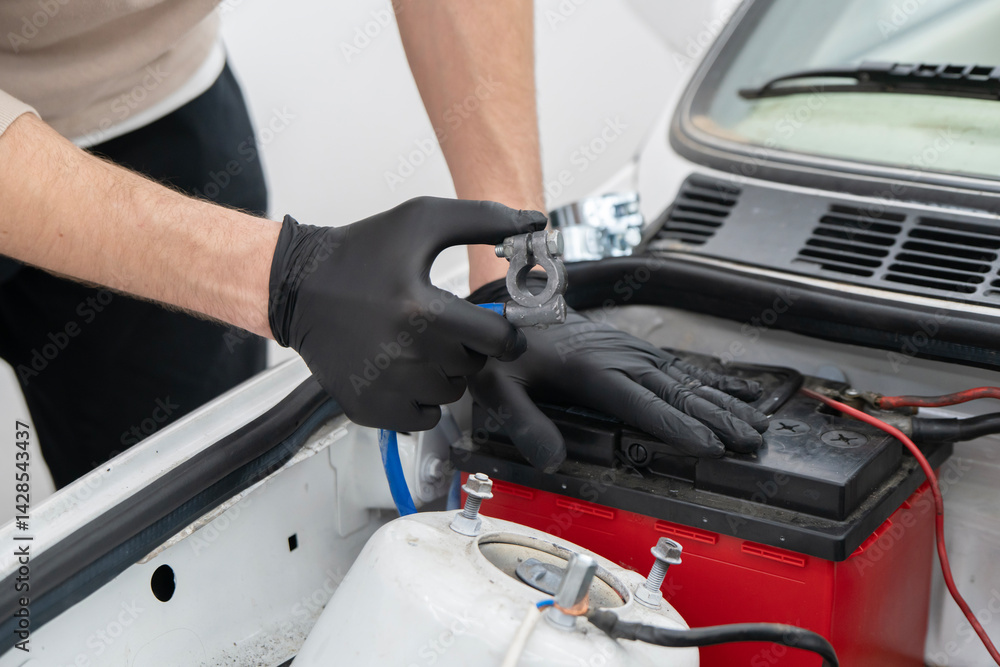 A skilled mechanic inspects the battery terminal in a bright auto studio, ensuring vehicle safety and reliability. A skilled mechanic inspects the battery terminal in a bright auto studio, ensuring vehicle safety and reliability.