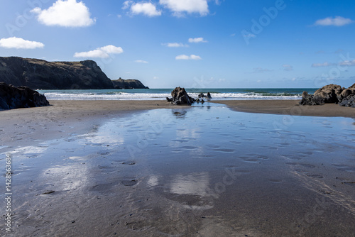 Traeth Llyfn beach on the Pembrokeshire coast, with the sky reflecting in the wet sand after the tide has retreated