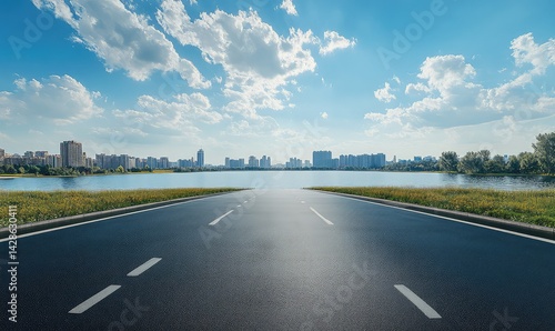 Asphalt road vanishing point leads to city skyline across tranquil lake under sunny sky