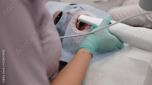 A young woman at the orthodontist's office. A 3D dental scan procedure for making mouthguards after wearing a braces system. Taking care of a smile