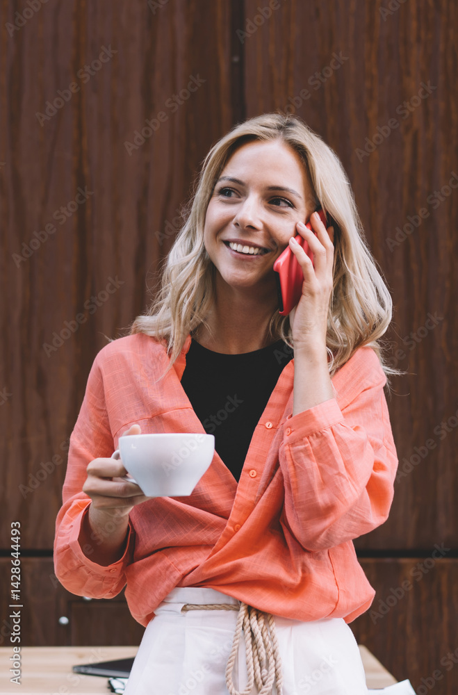 Young woman with cup of coffee and smartphone in creative cafe