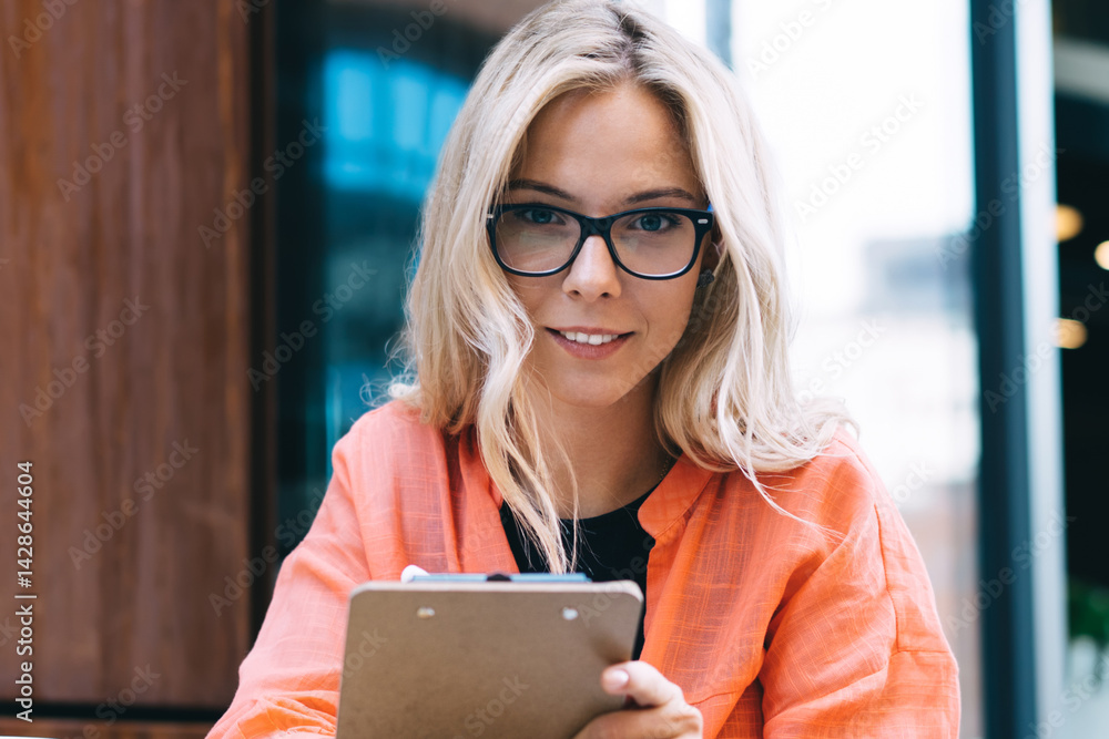 Portrait of creative female author holding planner prepare articles for publication in social networks and web pages, 20s attractive young woman looking at camera during freelance remote job