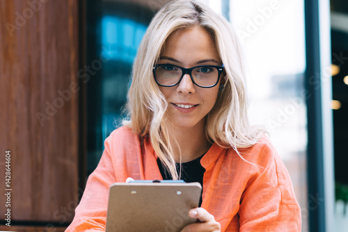 Obraz na płótnie Portrait of creative female author holding planner prepare articles for publication in social networks and web pages, 20s attractive young woman looking at camera during freelance remote job w salonie