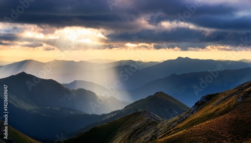 a cloudy sky with sun rays piercing through casting light over misty mountain ridges