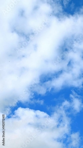 White clouds moving across blue sky in timelapse. Sky background.