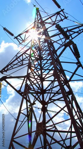 High-voltage supports with wires and insulators against the background of blue sky and flying clouds. Transmission of electricity by wires. Vertical video.