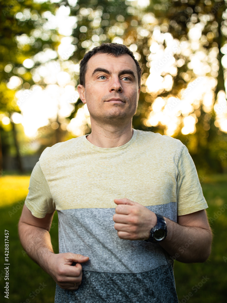 Portrait of handsome man outdoors running in park in spring