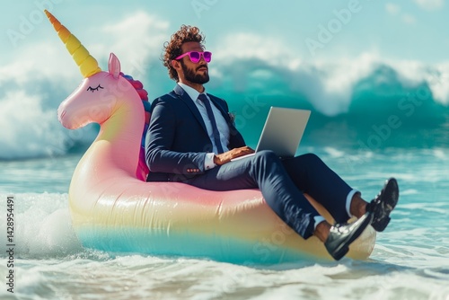 Businessman wearing suit and sunglasses enjoys work-life balance, working remotely from inflatable unicorn float in ocean waves