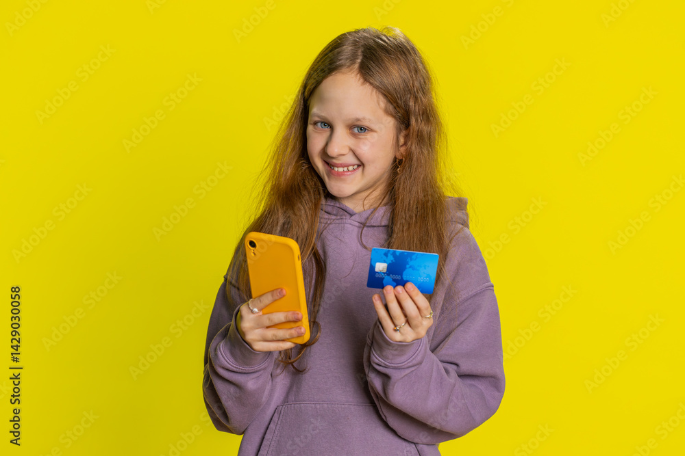 Portrait of happy teen child girl kid using credit bank card and smartphone while transferring spending money, purchases online shopping, ordering food delivery. Children isolated on yellow background Portrait of happy teen child girl kid using credit bank card and smartphone while transferring spending money, purchases online shopping, ordering food delivery. Children isolated on yellow background