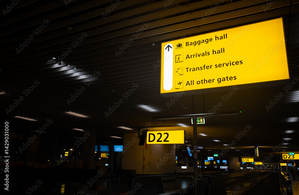 Airport signs showing arrivals, baggage, transfer services and gates guiding passengers