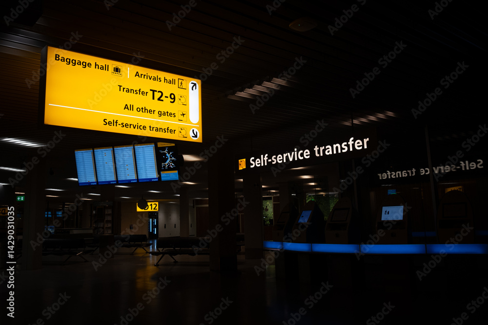 Airport terminal showing direction signs for baggage, arrivals, and transfer gates