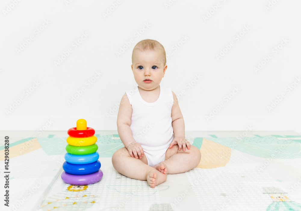 A 5-7 month old baby sits on the floor and plays with bright toys in his room. A 5-7 month old baby sits on the floor and plays with bright toys in his room.