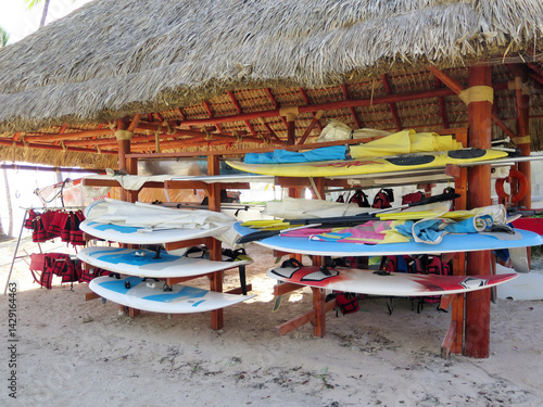 Surfboards and Life Jackets Under a Thatched Roof Hut on a Beach