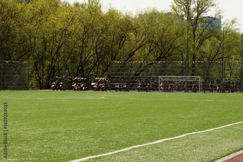 Soccer goal on big field with artificial green grass. Summer season. Outdoor sports activities.